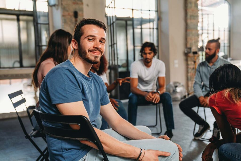 a man sits in a support group circle smiling