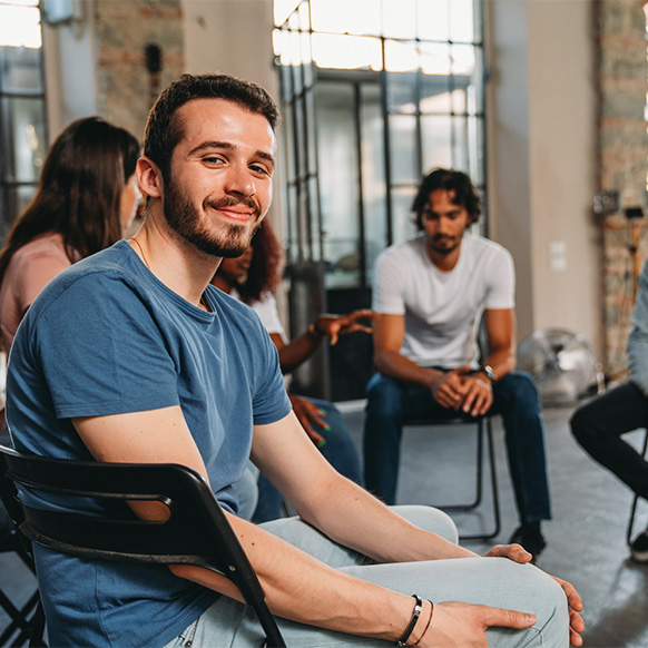 a man sits in a support group circle smiling