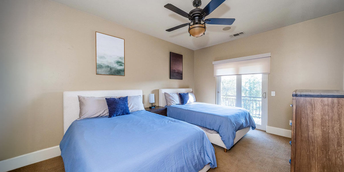 A shared bedroom with two beds, blue bedding, and a private balcony at a residential treatment center.