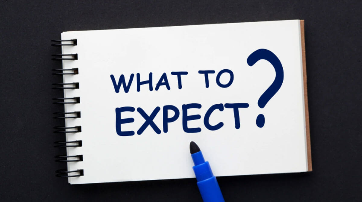 A notebook with the words “What to Expect?” written on it, alongside a blue marker.